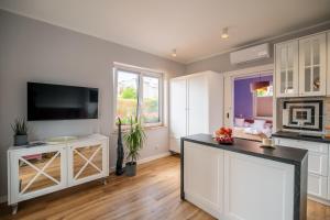 a kitchen with white cabinets and a flat screen tv at Mielnova Adults Only Jacuzzi & Sauna Apartamenty in Mielno +171 photos