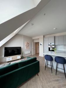 a living room with a green couch and a tv at The Apartments Lytham Square in Lytham St Annes
