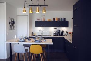 a kitchen with a table with chairs and wine glasses at Blue Sand - Appartement cosy-neuf à 500 m du bourg in Saint-Philibert +34 photos