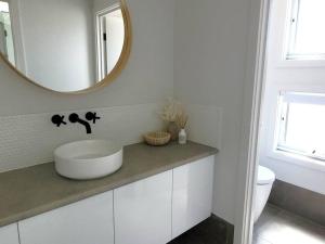 a bathroom with a white sink and a mirror at Whispering Winds in Wauraltee +3 photos
