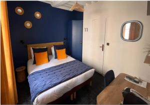 a bedroom with a bed with blue walls and orange pillows at Hotel Reine Mathilde in Bayeux