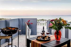 a table with wine glasses and flowers on a balcony at Sea Villa Vista in St. Helena Bay