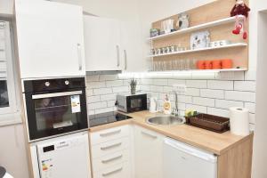 a small kitchen with white cabinets and a sink at Dora Apartman in Bačka Topola
