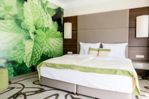 a bedroom with a large bed with a painting on the wall at Ambient Hotel & Aroma Spa in Sikonda