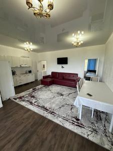 a living room with a red couch and a table at Симирам! in Korumdy