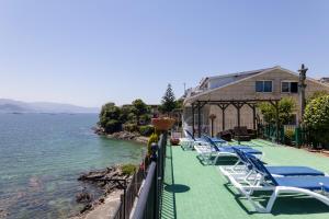 a row of lounge chairs on a balcony next to the water at Apartamentos Miramar Playa in Raxó