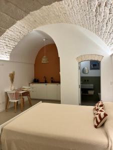 a bedroom with a bed and a table and a kitchen at Frida, suite in stile pugliese in Noci