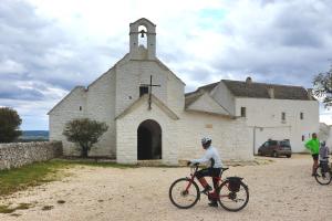 a man riding a bike in front of a church at Frida, suite in stile pugliese in Noci