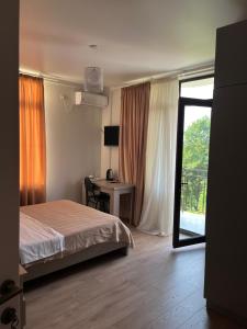 a bedroom with a bed and a desk and a window at Guest House in Batumi