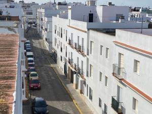 een stadsstraat met auto's geparkeerd naast witte gebouwen bij CONIL CENTRO MERCURIO solo FAMILIAS in Conil de la Frontera
