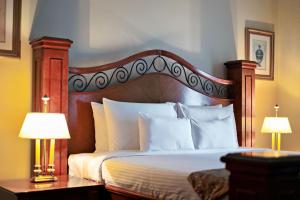 a bedroom with a bed with white pillows and two lamps at Waterfront Cebu City Hotel & Casino in Cebu City
