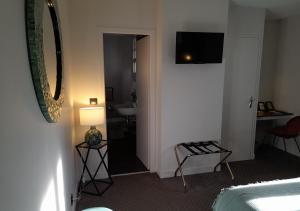 a hotel room with a bedroom with a bed and a television at Hotel Reine Mathilde in Bayeux