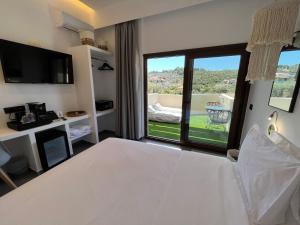 a bedroom with a white bed and a large window at Skopelos Holidays Hotel & Spa in Skopelos Town