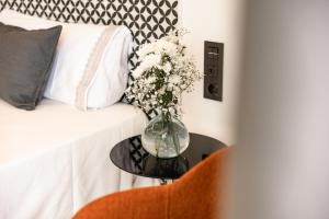 un vase de fleurs sur une table à côté d'un lit dans l'établissement Matilde Luxury by Grupo Matilde, à Las Palmas de Gran Canaria