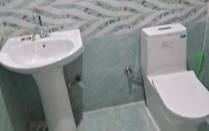 a bathroom with a white toilet and a sink at Uniyal Residency by StayApart in Nākuri