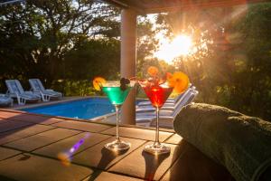 dos vasos de martini sentados en una mesa junto a una piscina en Leopard Walk Lodge, en Hluhluwe 28 fotos más