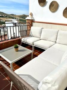 a balcony with white couches and a coffee table at Vistas del Valle in Valle de Abdalagís