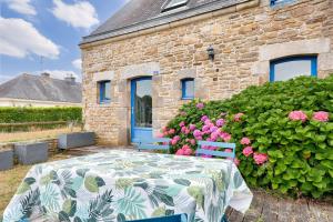 a table and chairs in front of a brick building with flowers at Vue sur mer, maison pour 7 Golfe du Morbihan in Sarzeau