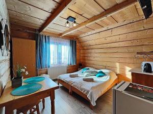 ein Schlafzimmer mit einem Bett in einem Holzzimmer in der Unterkunft Sichlański Zakątek in Murzasichle