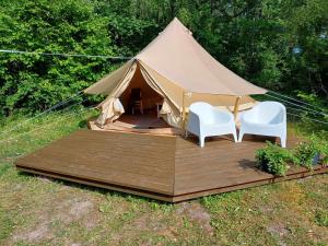 una tenda con due sedie bianche e un ponte di legno di Trummi glämping ja korstnata saun a Hiiumaa