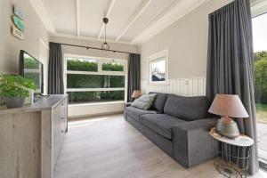 a living room with a couch and a window at Prinsenhof 13 - Ouddorp in Ouddorp
