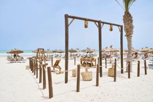 a beach with chairs and umbrellas and people at Iberostar Waves Mehari Djerba in Taguermess