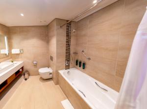 a bathroom with a tub and a toilet and a sink at Hilton Garden Inn Nairobi Airport in Nairobi
