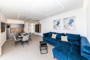 a living room with a blue couch and a kitchen at Villa Pavlina in Kaštela