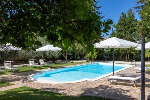 a swimming pool with two chairs and an umbrella at Tenuta dell'Inviolata Guest House in Velletri