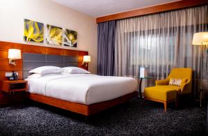 a hotel room with a bed and a yellow chair at Hilton Garden Inn Nairobi Airport in Nairobi