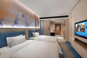 a hotel room with two beds and a flat screen tv at 东莞大朗希尔顿欢朋酒店 in Huangcaolang