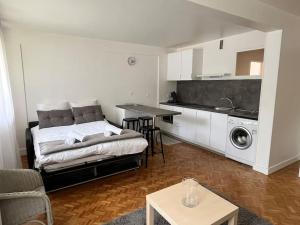 een woonkamer met een bed en een keuken bij Harmonie - Affaires & Loisirs à Rueil in Rueil-Malmaison