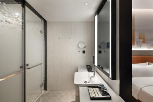 a bathroom with a sink and a bed and a mirror at 东莞大朗希尔顿欢朋酒店 in Huangcaolang