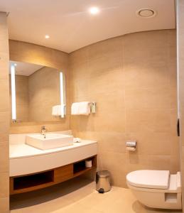 a bathroom with a sink and a toilet and a mirror at Hilton Garden Inn Nairobi Airport in Nairobi