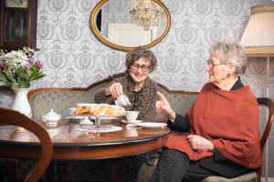 zwei ältere Frauen sitzen am Tisch und essen Essen in der Unterkunft Gamle Fengselet Kulturhotell in Stord