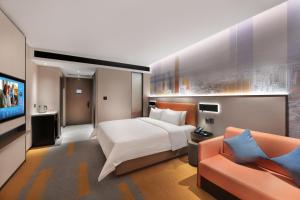 a hotel room with a bed and a couch at 东莞大朗希尔顿欢朋酒店 in Huangcaolang
