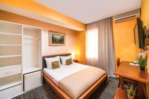 a bedroom with a bed and a desk and a television at Hotel Kerber in Podgorica