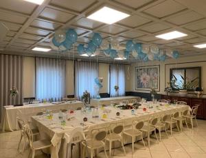 a large long table with white tables and blue balloons at La Sosta Hotel in Vestone