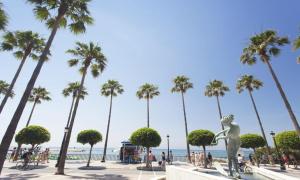 una statua di fronte a una spiaggia con palme di Penthouse with private pool, hot tub jacuzzi with sea views and chill-out zone, close to the sea a Marbella