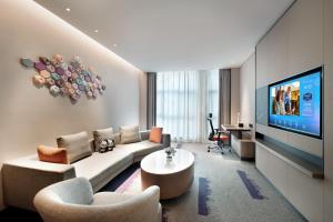 a living room with a couch and a tv at 东莞大朗希尔顿欢朋酒店 in Huangcaolang