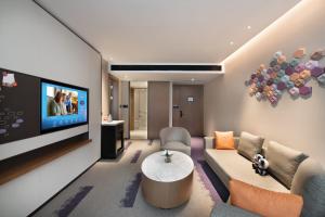 a living room with a couch and a tv at 东莞大朗希尔顿欢朋酒店 in Huangcaolang