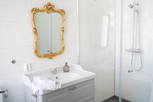 ein weißes Badezimmer mit Waschbecken und Dusche in der Unterkunft Gamle Fengselet Kulturhotell in Stord