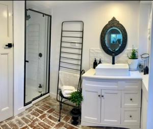 a bathroom with a sink and a mirror and a shower at ONE WEE COTTAGE Bring your dog and enjoy a cosy romantic winter fireside stay in Healesville