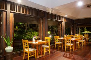 a restaurant with wooden tables and yellow chairs at Baan Krating Phuket Resort -SHA Plus in Nai Harn Beach