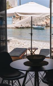a table with chairs and an umbrella on a beach at Anastasia Kimolos in Kimolos