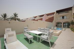 a patio with a table and chairs and a building at Durrat Al Arous - Rose Beach Villas in Durat  Alarous
