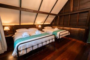 two twin beds in a room with a attic at Hom Klin Paa หอมกลิ่นป่า in Kanchanaburi City