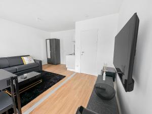 a living room with a couch and a flat screen tv at Rive Droite au Portes de Paris in Le Blanc-Mesnil