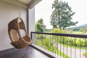 a balcony with a rattan swing and a view at Chatrium Golf Resort Soi Dao Chanthaburi in Ban Thap Sai
