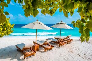 a group of chairs and umbrellas on a beach at Sand Inn Residence in Kamadhoo